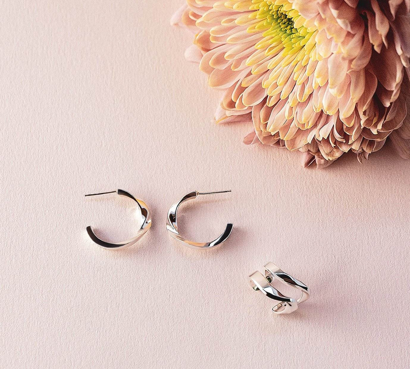 Linea Earring Set featuring sterling silver mini hoops and ear cuff on pink background with flower