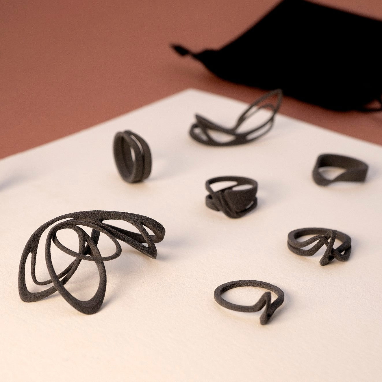 Set of black nylon ring samples from LACE collection displayed with a black velvet pouch on a beige surface