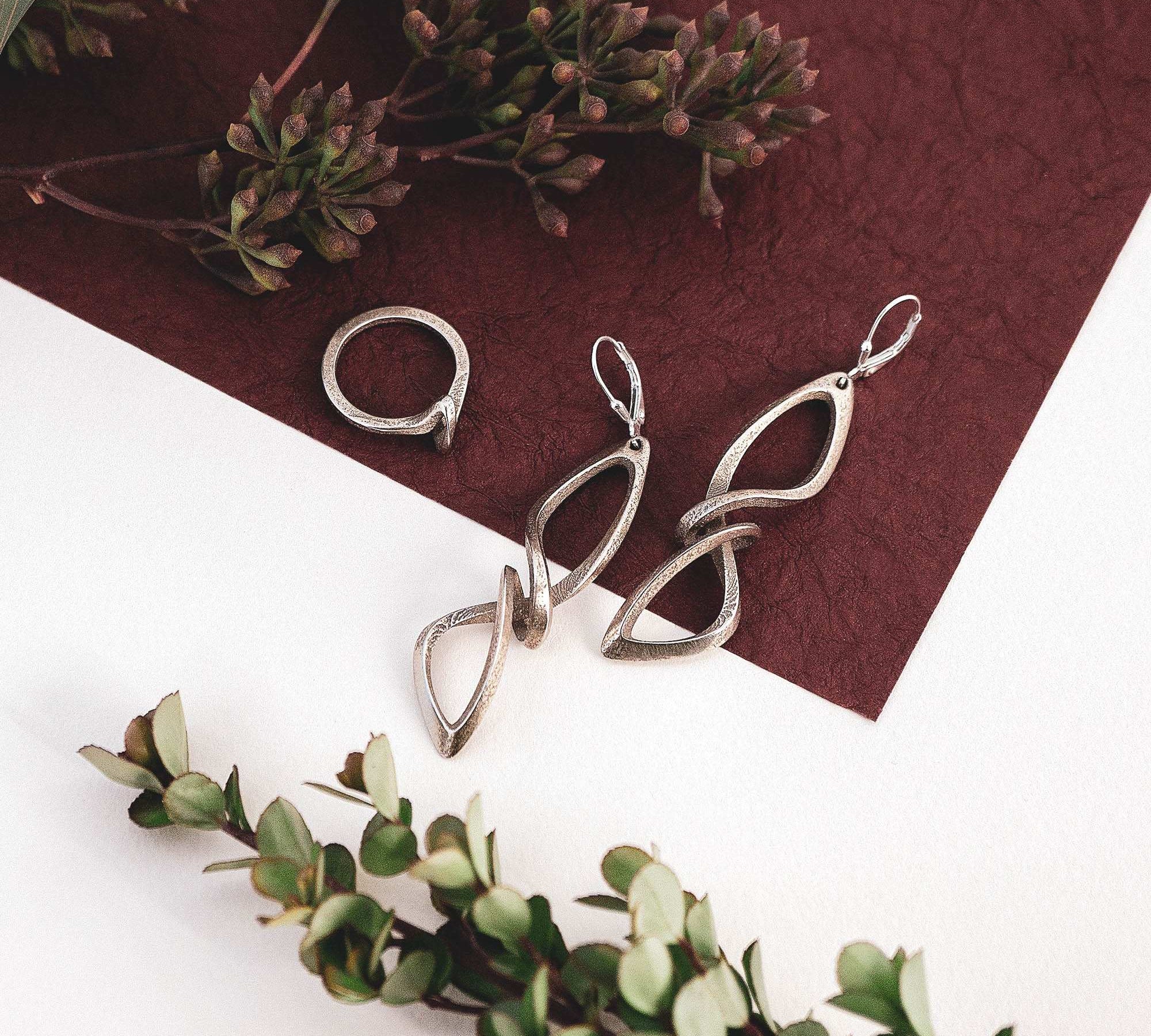 Centri Steel Earrings and Sera Steel Ring gift set with twisting linework design in stainless steel on textured background