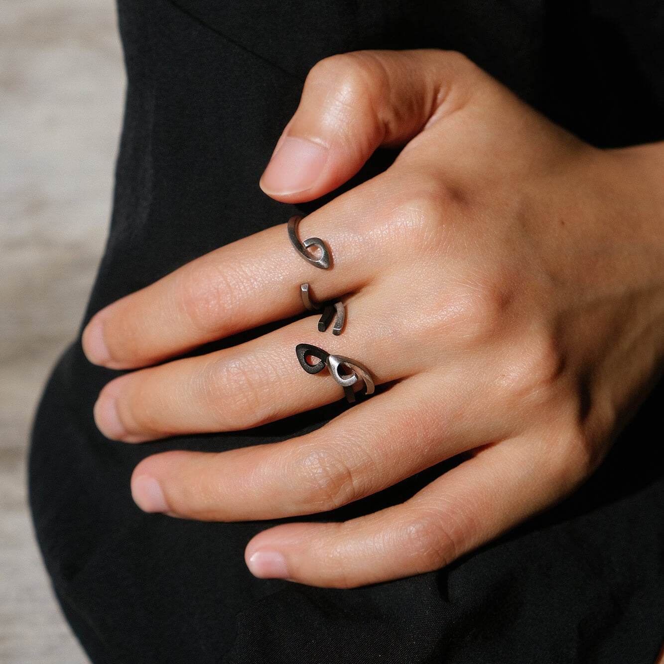 Hydra Stainless Steel Ring with open oval loop design worn on hand, black and silver finish, modern curved band style