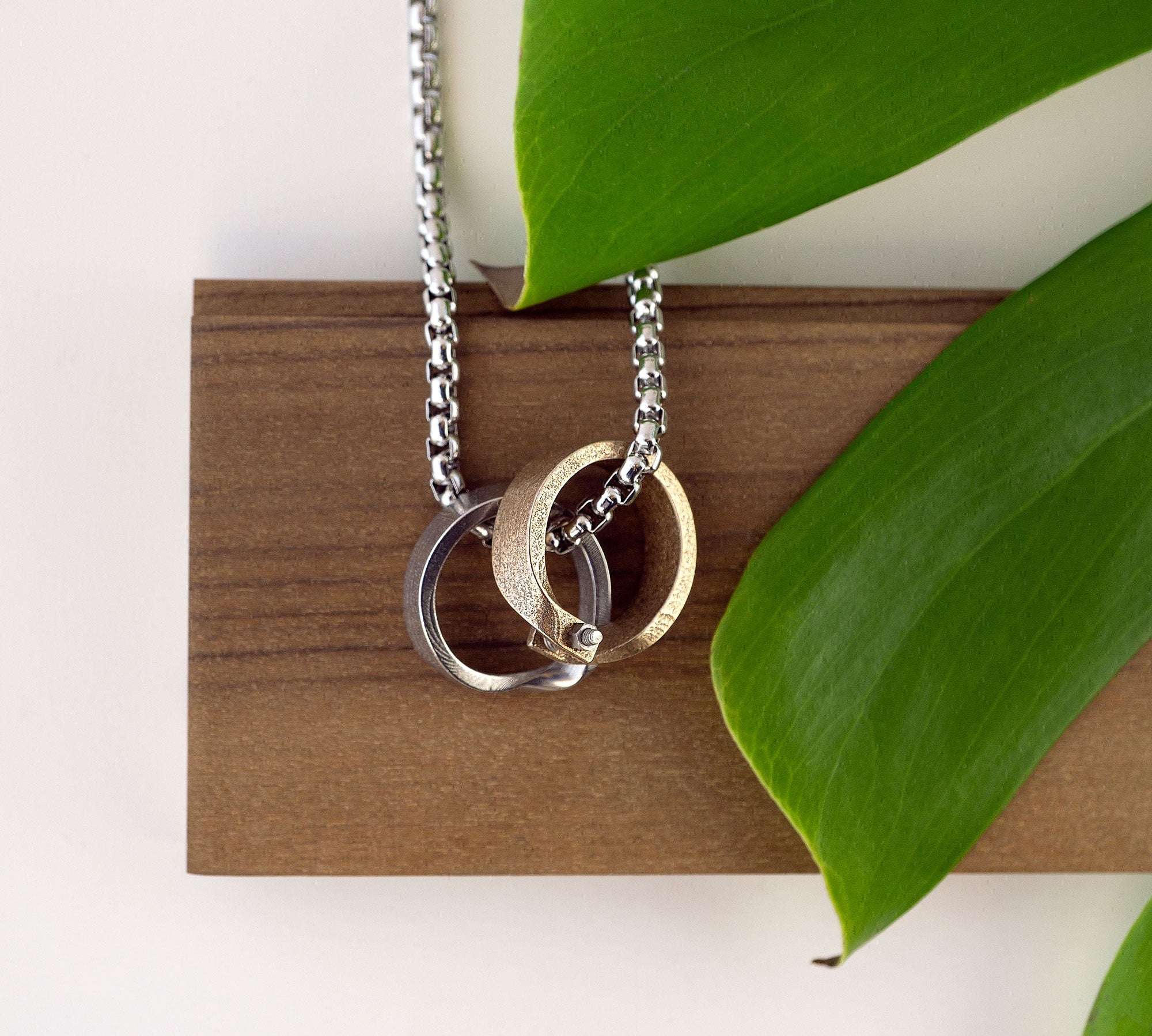 Machina Gift Set stainless steel and bronze men's rings with chain necklace on wooden display with green leaves